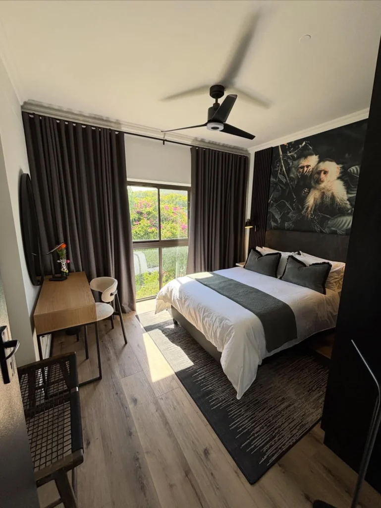 Airbnb Decor Ideas That Increase Bookings (Stylish, Cozy & Guest-Approved) 3 Modern Airbnb bedroom with dark accent wall, artwork, and cozy lighting