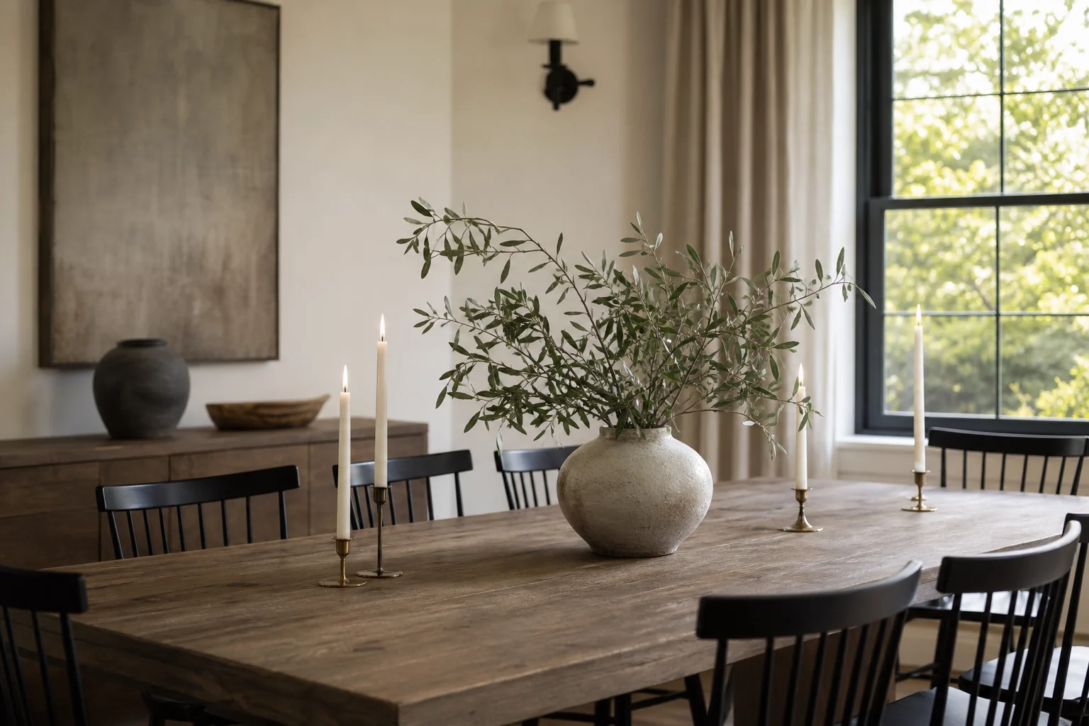 Low dining table centerpiece with leafy branches and neutral ceramics