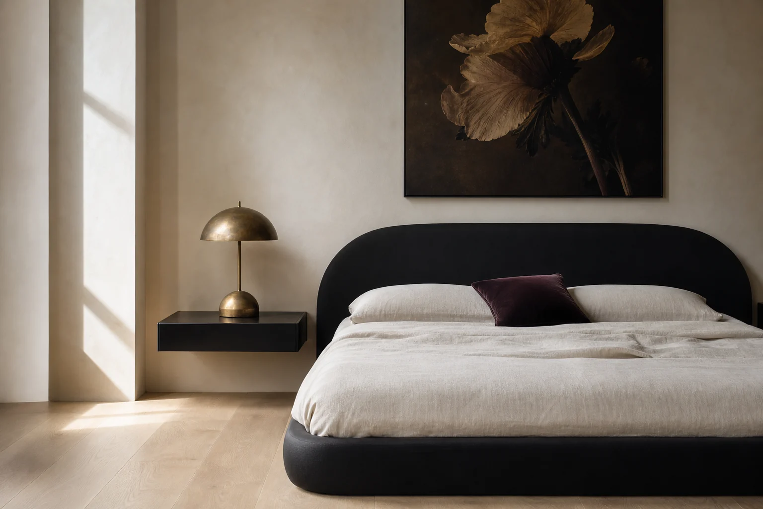 Modern minimal Black Nouveau bedroom with curved black furniture, ivory bedding, one botanical artwork and warm brass light