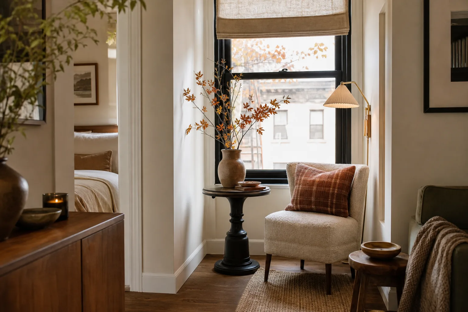 Tiny fall window nook with a slim chair, pedestal table, plaid pillow and branches